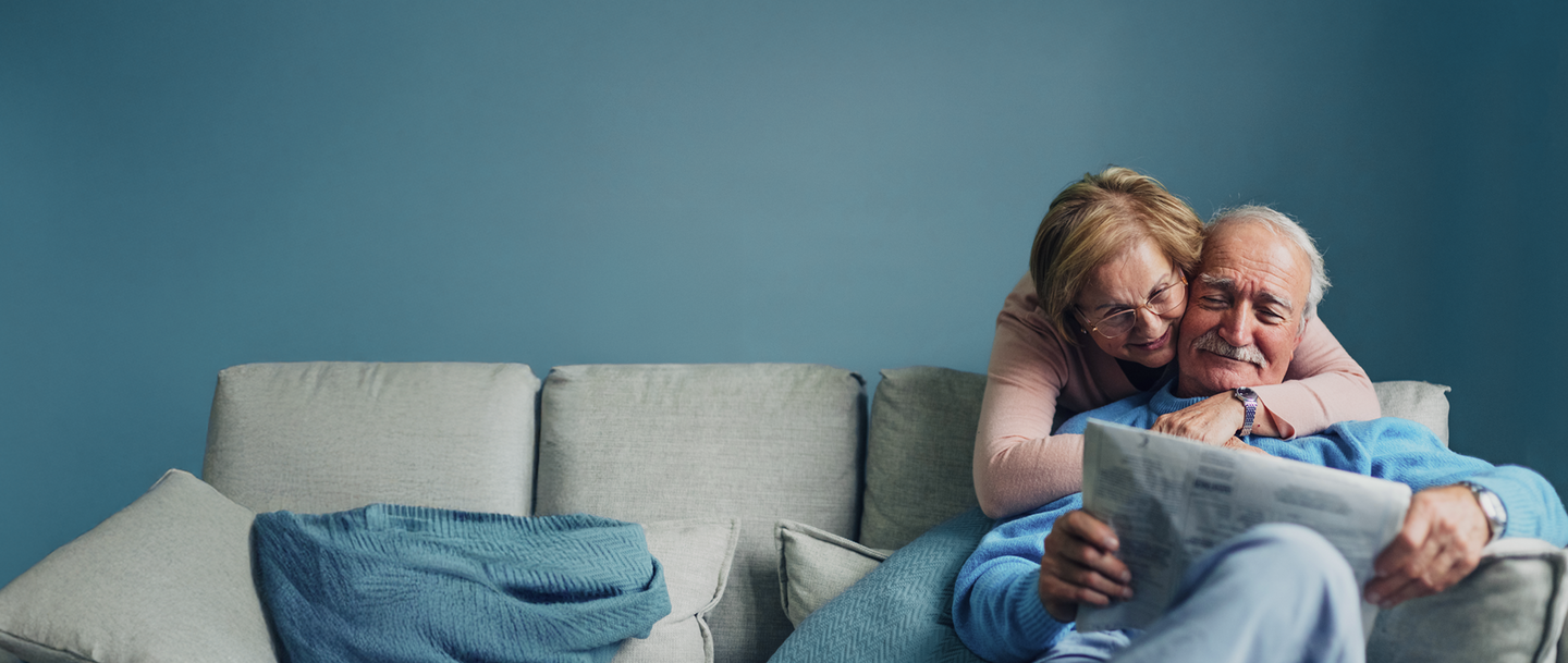 Ein Porträt eines älteren Paares, das zu Hause entspannt, redet, liest, kuschelt, genießt.